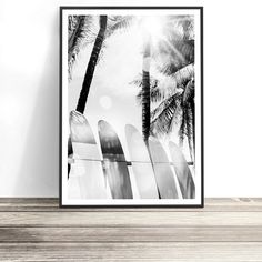 a black and white photo of surfboards in front of palm trees on the beach