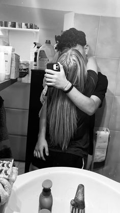 a woman standing in front of a bathroom sink holding her hair up to her face