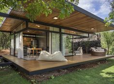 an outdoor living area with wood flooring and glass walls