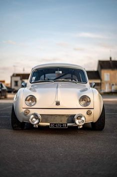 an old white car parked in a parking lot