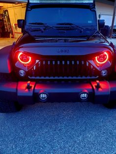 the front end of a black jeep with its lights on