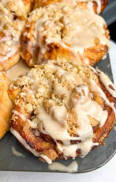 cinnamon rolls with icing and crumbs are on a plate, ready to be eaten