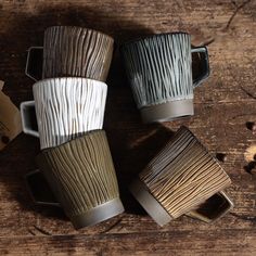 four coffee mugs are stacked on top of each other, one is made out of wood