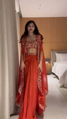 a woman in an orange outfit standing next to a bed