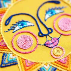 a close up view of some embroidery on a piece of yellow fabric with blue and pink thread