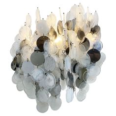 a chandelier made out of metal discs and glass disks hanging from the ceiling