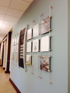 a wall with several pictures on it in an office building or waiting area, along with other walls and flooring