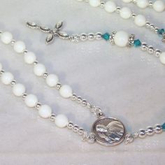 Choose your pearl and crystal color, metal finish (silver or gold), cross and connector. All of my pieces are made-to-order (custom). If you don't see what you want, convo me and we'll make it together. Rosary of 6mm and 8mm Swarovski pearls (shown with Ivory Gem) with silver bead caps capped off with 4mm Swarovski crystal bicones (shown in Light Turquoise). The beads separating the decades are 4mm silver (metal) beads. The medal (connector) shown on this listing is the current pop, Pope Francis Silver Jewelry With 8mm Beads For First Communion, Spiritual White Cross Jewelry, Elegant White Miraculous Medal Jewelry, White Miraculous Medal Spiritual Jewelry, White Necklace With Miraculous Medal And Round Beads, White Sterling Silver Jewelry With Spacer Beads, Silver Spiritual Jewelry For First Communion, Spiritual Silver Jewelry For First Communion, White Spiritual Crucifix Jewelry