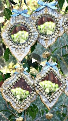 three decorative ornaments hanging from a tree in front of some trees with leaves on them