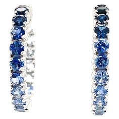 Beauty, luxury and sophistication are epitomized in this pair of elegant ombre sapphire hoop earrings featuring a stunning, unusual collection of blue and white sapphires. Over 4 carats of brilliant sapphires blending seamlessly from light to rich royal blue, bringing these 14k white gold "inside out" hoop earrings to life. Earrings measure 1 inch in diameter and have a secure and comfortable hinged safety closure. The perfect size for daytime and evening wear, casual and special occasions, these earrings are a beautifully original version of a timeless classic! Matching bracelet (BR-430) sold separately 32 round sapphires, 3.00mm, 4.26 carats total Sapphire Hoop Earrings, Earring Video, London Blue Topaz Earrings, Gold Diamond Hoop Earrings, Sapphire And Diamond Earrings, White Gold Hoops, Round Sapphire, Blue Topaz Earrings, Topaz Earrings