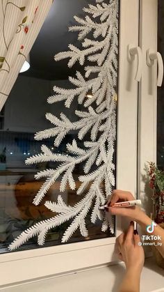 a person is painting a window with white paint on the outside and side of it