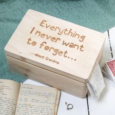 a wooden box with writing on it sitting next to an open book and playing cards