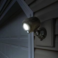 a close up of a light on the side of a house with a garage door in the background