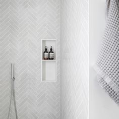 a white bathroom with herringbone wallpaper and shelf for soaps, lotion and hand sanitizers