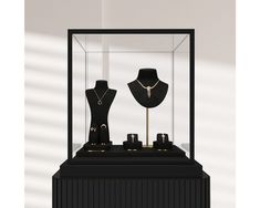 two mannequins are in a glass case with necklaces on display next to each other