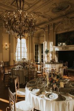 an elegant dining room with chandelier and white table cloths set for dinner