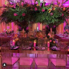 the table is set with pink linens and purple flowers, candles, and greenery