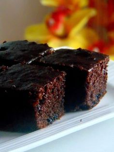 two pieces of chocolate cake on a white plate with flowers in the backgroud