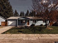 a blue house sitting on the side of a road next to a green field and trees