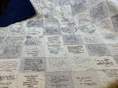 a quilt with writing on it sitting on top of a bed