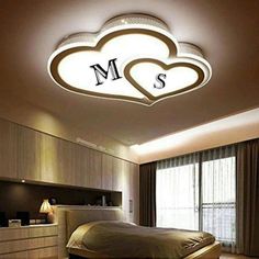 a bed room with a neatly made bed and a heart shaped light above the headboard