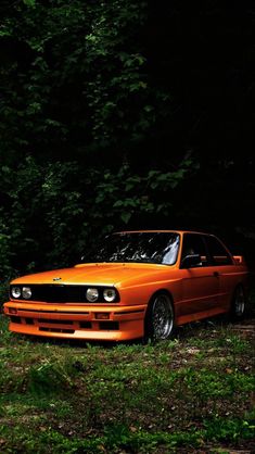 an orange car parked in front of some trees