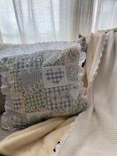 a close up of a pillow on a bed with a blanket and window in the background