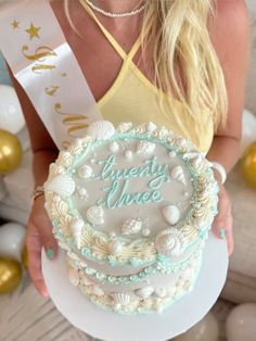 a woman holding a cake with the words twenty once on it in front of balloons