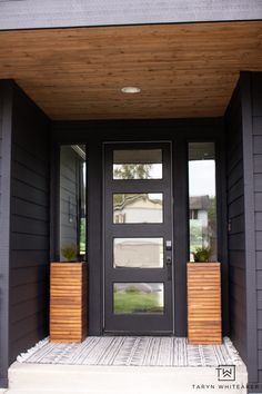 a black front door with two planters on it