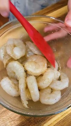 a person cutting up some shrimp in a bowl