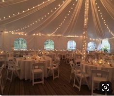 the inside of a large tent with tables and chairs set up for an outdoor function