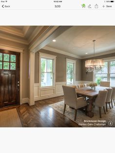 a dining room table and chairs in front of two windows with wood trimmings