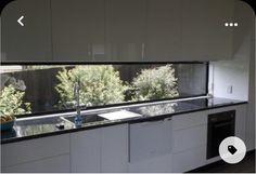 an empty kitchen with white cabinets and black counter tops is seen from the outside window