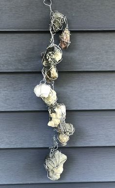 a bunch of shells hanging from a chain on the side of a house with blue siding