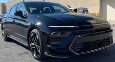 the front end of a black car parked in a parking lot