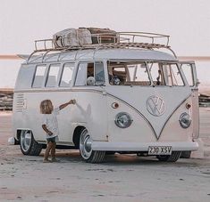 two people standing in front of an old vw bus