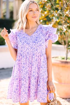 Look your best with our ditsy floral Lavender Purple Babydoll Dress! Enjoy the casual-cute styling that will make heads turn, radiating confidence and feeling your best. Plus, who doesn't love a dress that you can wear with heels or sneakers?! This dress features short ruffled sleeves, a v-neck, babydoll fit, tiered body, and a ditsy floral print. Material has no amount of stretch.Cam is wearing the small. Cute Pink Mini Dress With Ditsy Floral Print, Trendy Mini Dress With Ditsy Floral Print For Spring, Trendy Purple Short Sleeve Dress, Spring Purple Floral Mini Dress, Spring Purple Floral Print Mini Dress, Purple Floral Print Mini Dress For Spring, Cute Purple Mini Dress, Cute Purple Mini Dress For Spring, Lavender Floral Print Cotton Dress