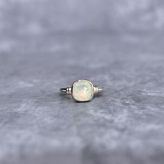 ✦ Discover the mesmerizing allure of our Natural Opal Ring. Meticulously set in fine silver, this ring features a cushion-shaped natural opal, known for its captivating play-of-color. Perfect for day-to-day elegance or social gatherings, its unique shimmer effortlessly transitions from daytime charm to evening chic. Whether you're indulging yourself or selecting a heartfelt gift, this ring adds a dash of opalescent magic to any look. 💎  Please Note As with all Natural Gemstones The colors and i Bridesmaid Gifts Unique, Natural Opal Ring, Opal Ring, Raw Gemstones, Heartfelt Gifts, Natural Opal, Moon Stone, Ring For Women, Stackable Rings