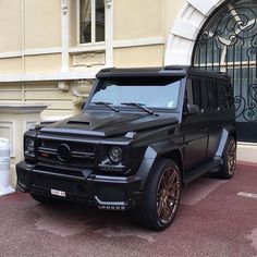 a black mercedes g - class parked in front of a building