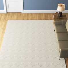 a living room with blue walls and white rugs on the hardwood floor, along with a beige sectional sofa