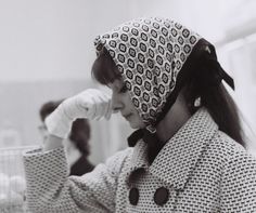 black and white photograph of a woman wearing a hat with her hands on her head