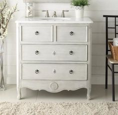 a white dresser sitting next to a bathroom sink