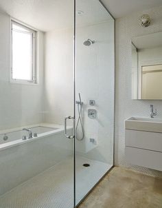 a bathroom with a walk in shower next to a sink and a bathtub under a window