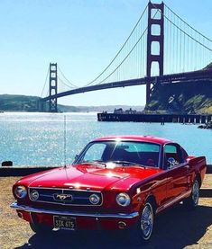 an old red car parked in front of the golden gate bridge