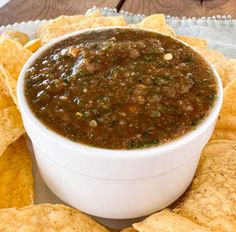 a white bowl filled with salsa surrounded by tortilla chips