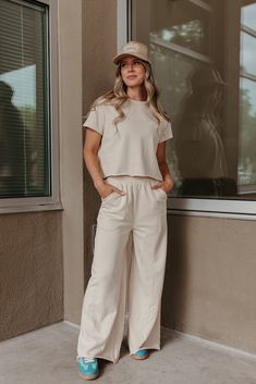 Look super cute and feel comfortable all day in THE SARA SET IN CREAM! This travel outfit includes a raw hem, cropped short sleeve sweater and wide leg pants with an elastic waist. Perfect for wearing all day, this set is both stylish and comfortable. Paired with THE HOWDY DARLIN' TRUCKER HAT IN BEIGE & THE FIERCE SNEAKERS IN GREEN Sold as a set. Top: Short sleeve Round neck Raw hem Slightly cropped Loose fit 80% polyester, 20% spandex Bottom: Wide leg Pockets Relaxed fit Elastic waistband Raw h Cream Loose Pants Outfit, Casual Cotton Sets With Elastic Waistband, Casual Cropped Hem Bottoms For Spring, Cotton Sets With Elastic Waistband And Short Sleeves, Casual Cotton Wide Leg Sets, Casual Cropped Hem Bottoms For Summer, Casual Sets With Elastic Waistband And Wide-leg Pants, Casual Set With Elastic Waistband And Wide-leg Pants, Cotton Wide Leg Loungewear Set