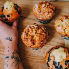 a person's arm with tattoos on it next to some muffins