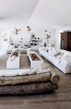 a living room filled with white furniture and lots of pillows on top of wooden flooring