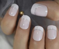 a woman's hands with white and silver nail polishes on their nails,