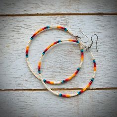 two bracelets with multicolored beads are sitting on a wooden surface